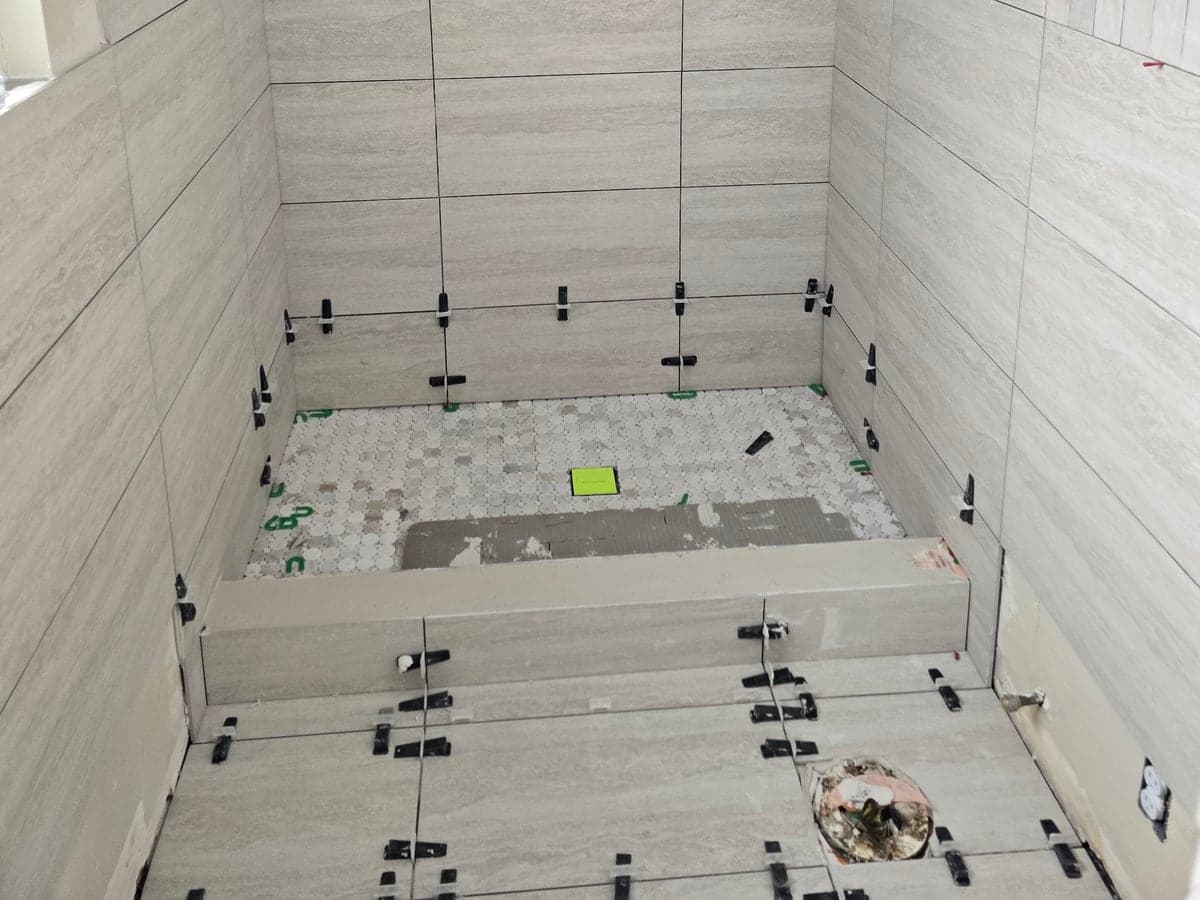 Finished large-format tiled shower with a mosaic niche and completed shower pan.