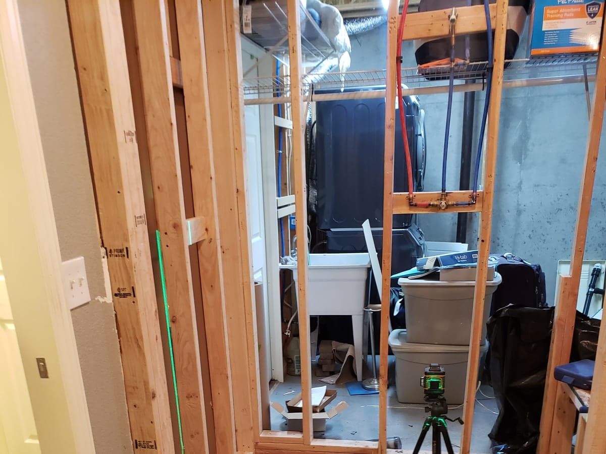 Room with an exposed stud partition and protected flooring during a remodel.